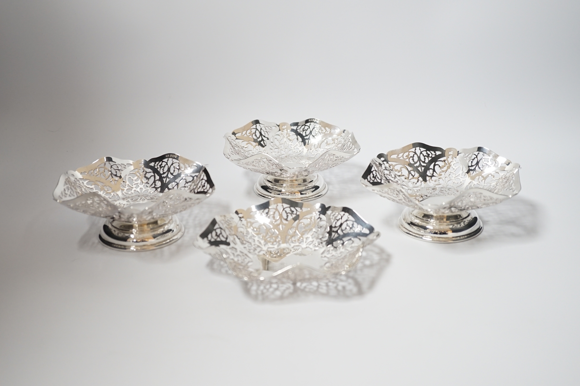 A set of three Elizabeth II pierced silver bonbon dishes, William Bush & Son, Sheffield, 1962, 14.2cm and one other similar silver shallow dish, 16oz.